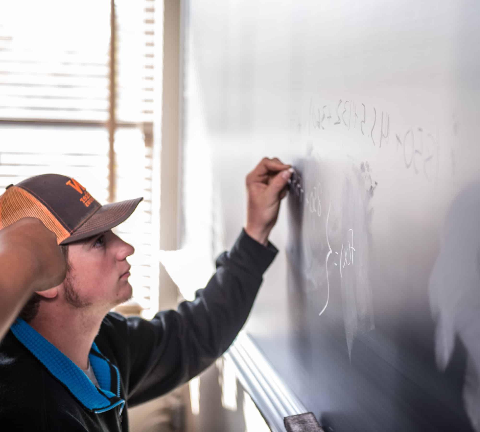 Math student working out problem on chalkboard